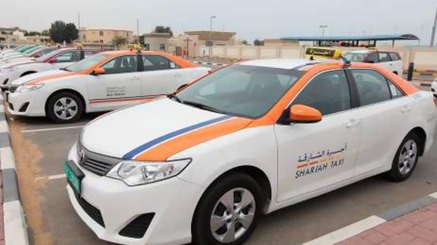 Sharjah taxi white cab with orange and blue lines, taxi logo on the side of the door and signature taxi signage on top