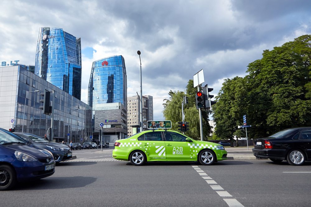Vilnius, Lithuania Taxi neon green taxi with white details and signature roof sign roaming the streets, the sign has an ad on it for a popular fast food chain