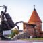 statue and red brick building at daytime.