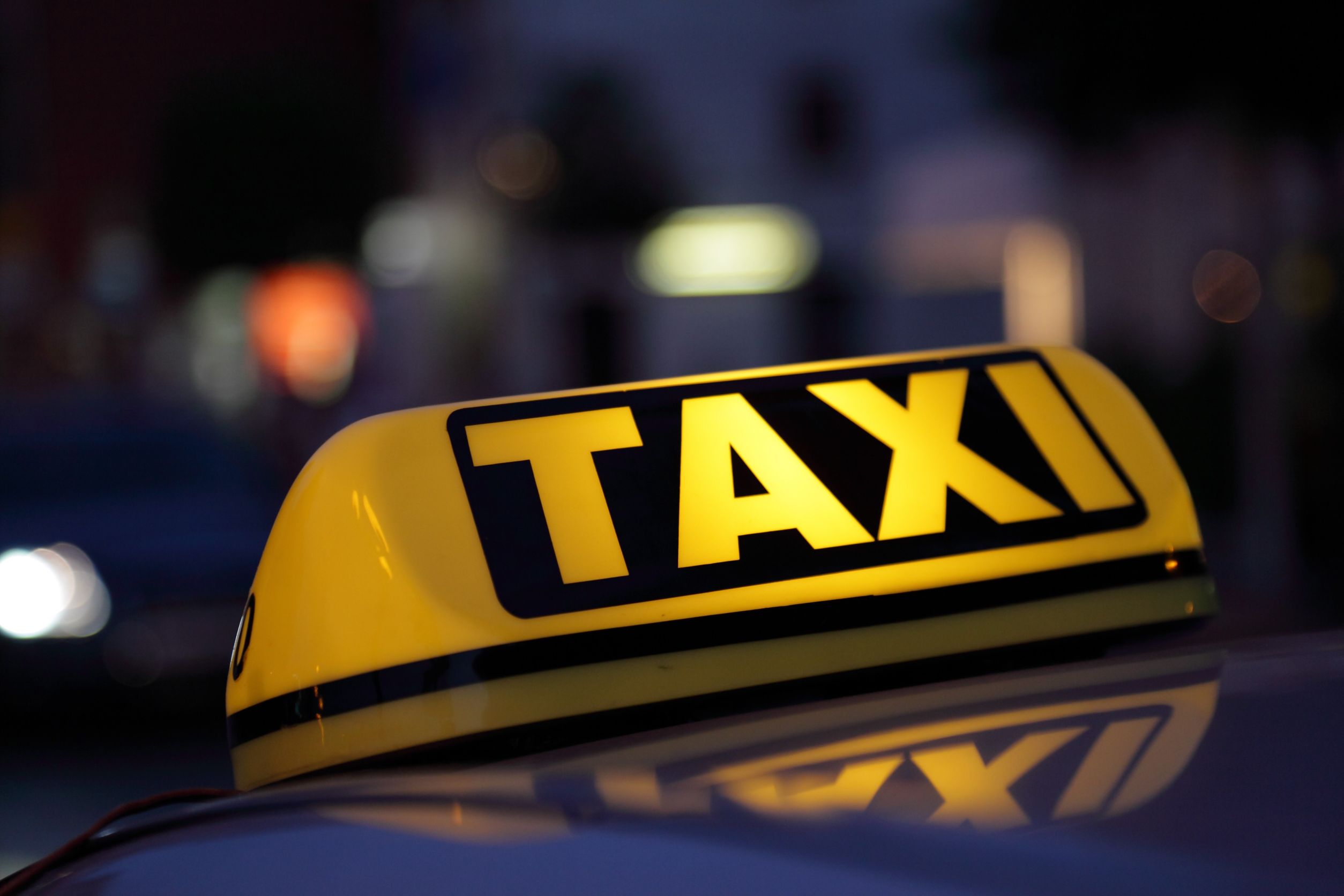lighted taxi sign in yellow and black at night time