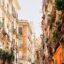 zoomed in shot of traditional italian-flat home fronts in yellow, orange and salmon pink and potted plants at the balconies