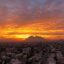 cityscape of Monterrey, a mountain appears in the background with a backdrop of an orange and baby blue and pink sunset sky in Monterrey Mexico