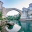 concrete bridge over turquoise body of water under a clear sky