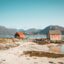 two houses beside body of water under a light blue clear sky in Tromso, Norway