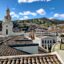 Quito city center during daytime with blue sky and mountains in the background.