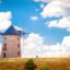 Scenic windmill in a golden field in Ankara, Turkey, with a blue cloudy sky above.