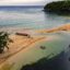 seashore surrounded by green bushes and trees and a little boat in the center in Ocho Rios, Jamaica