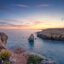 Rocky coastline at sunset on the island of Menorca, with calm blue waters and dramatic cliffs—ideal for travelers booking a taxi at Menorca Airport to reach scenic seaside spots like this.