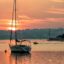 A sailing yacht anchored in a bay in Alvor at sunset.