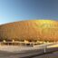 A view of Lusail Stadium, a golden stadium with blue skies above.