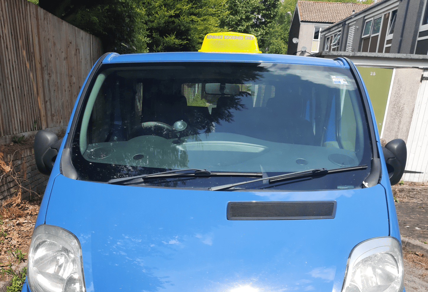 Manchester Airport Taxi (Minivan) Front view of a blue Manchester Airport taxi minivan with a yellow sign on the roof.