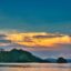 A setting sky over an island in the ocean.
