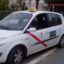 Side view of a white Almeria taxi with red stripe on the door and yellow taxi sign on the roof.