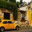 A yellow beetle car outside a yellow historical building in Antigua.