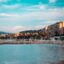 A sandy beach with blue waters and apartment buildings behind.