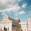Architectural building against a blue sky in foreground, with Leaning Tower Of Pisa seen in background in Italy