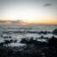 yellow and orange sunset over dark ocean waters and rocks