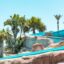 View of a bright blue waterslide at a Roquetas de Mar waterpark, with palms and rocks surrounding the slide.