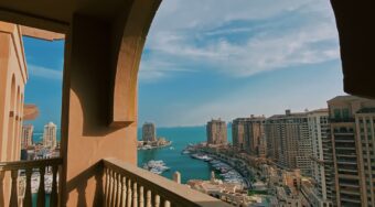 A view of Doha's marina and tall buildings from an arched balcony.