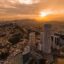 Aerial view of Guayaquil at sunset with skyscrapers and an orange, cloudy sky.