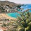 colorful sandy beaches surrounded by buildings and hills behind a palm tree