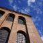 View of a brick building with large windows and blue skies above.