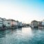 Heritage buildings in pastel colours of yellow, blue and white lining a waterway in Zurich city center.