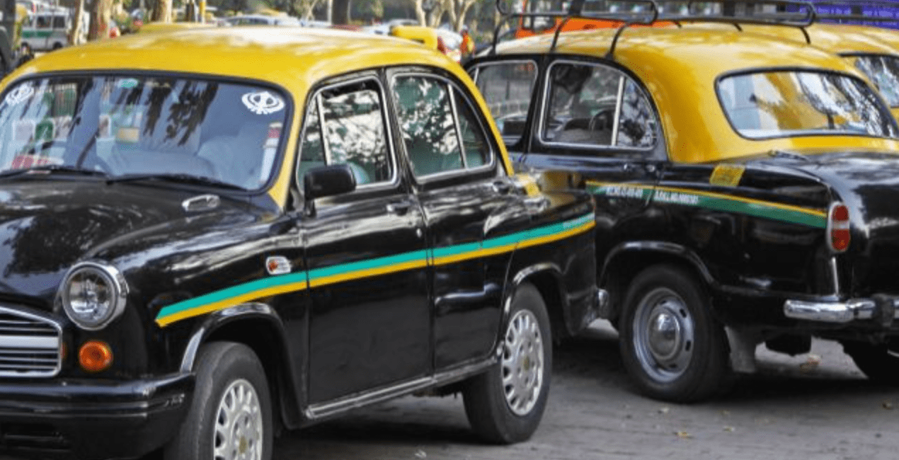 taxi vehicles in Goa, two black vehicles with a yellow roof and two stripes on the sides, one in green, one in yellow