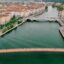 bridges over green colored water with streets and buildings on both sides