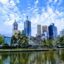 A view of Melbourne across the reflective water under a cloudy blue sky