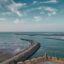 A view of the ocean with a large sea wall and the rooftop of a fort.