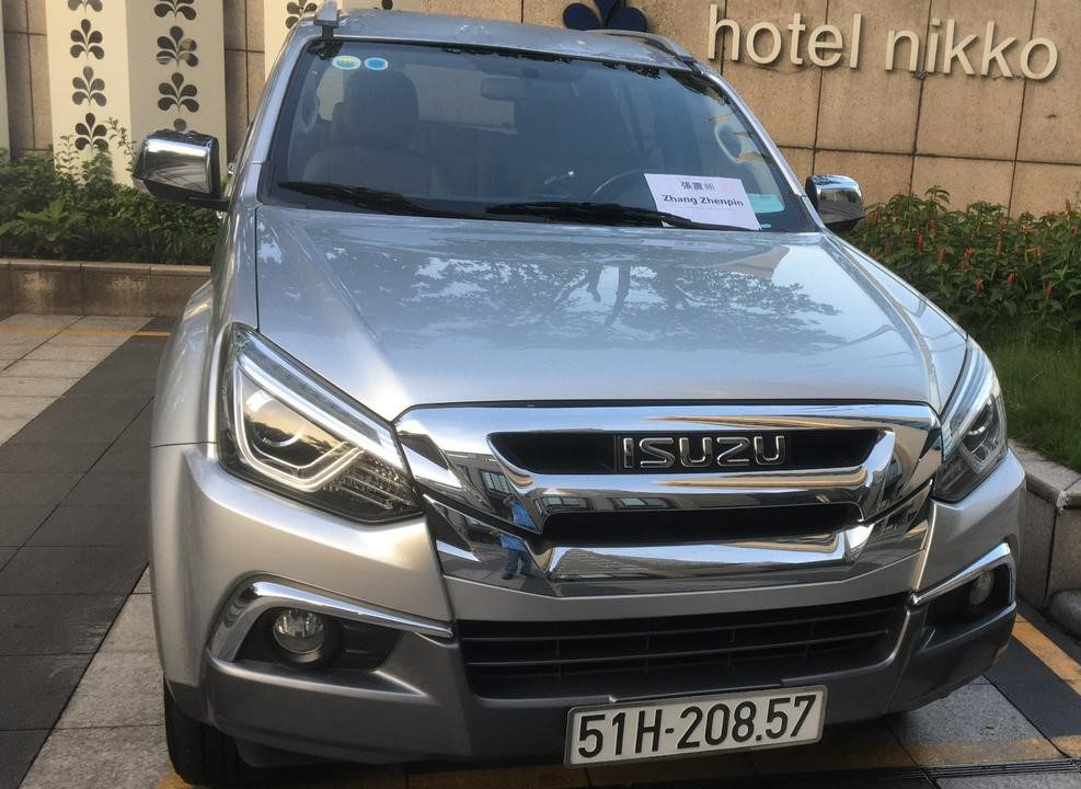 A silver Ho Chi Minh Airport taxi sedan parked outside of a hotel.