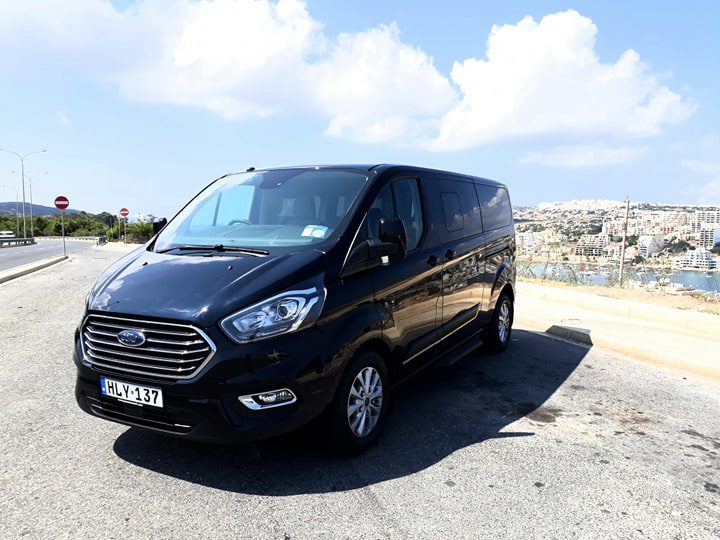 A Malta Airport taxi - Welcome Pickups Side view of a black Malta Airport taxi (minivan)
