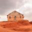 A small house situated on top of a red sand dune