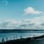 Blue ocean waters span under a cloudy sky.