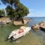 Three small boats docked in a calm seaside alcove next to a pier