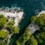 Aerial view of the ocean crashing against rocky limestone cliffs with trees on top of them