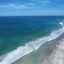 A long stretch of coast with a white sandy beach and turquoise water.