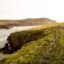 Dingle waterway and green hillside with a fence lined beaten walking path