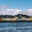 Homes line a scenic waterway under a cloudy blue sky