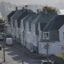 Street in Haugesund lined with two-story homes with city buildings and water in the background.
