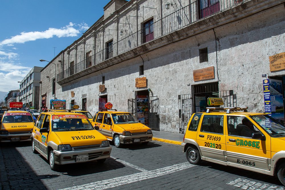 Yellow Arequipa taxis drive along a local road.