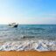 A beach and a fishing boat in the water off the coast in Batu Feringghi.