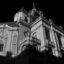 An upwards view of a white Baroque style building lit up at night against a black sky.