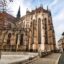 A large sandstone coloured Gothic-style cathedral set in a town square.