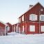 Snow covers the ground and yards outside red buildings in Lulea, Sweden.