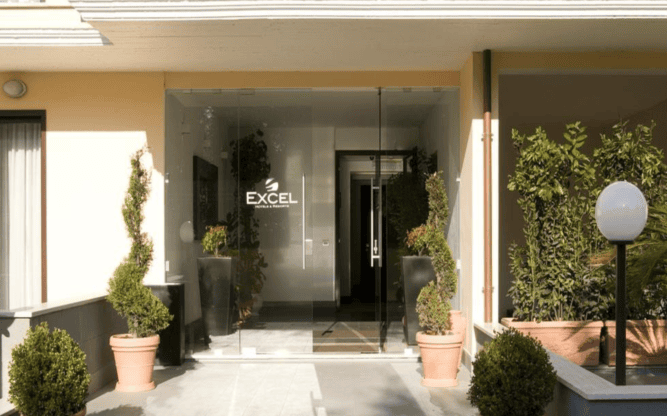 Front door of Quality Hotel Excel, with potted plants either side of the door.