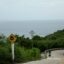 Hazy sky over the ocean with a steep road and trees in the foreground.