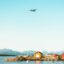 A plane flies over water, mountains, and cabins in Molde, Norway.