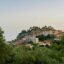 View through dense trees to homes on a hill in Parga, Greece.